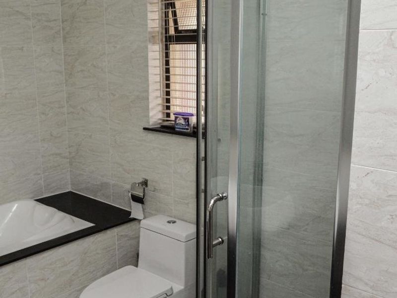 A modern bathroom featuring a glass-enclosed shower, a built-in bathtub, and a toilet, finished with neutral wall and floor tiling.