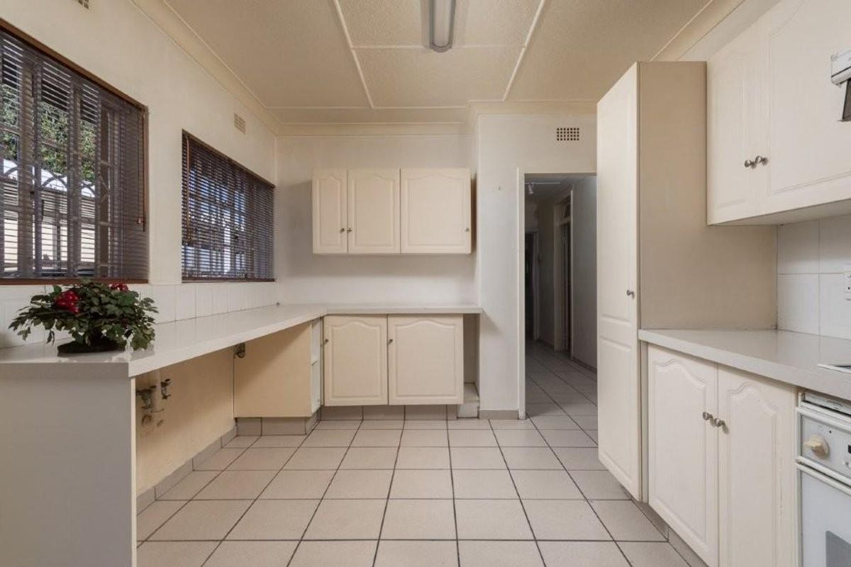 A dated kitchen featuring neutral cabinetry, tiled flooring, and built-in oven, offering a functional layout with potential for modern renovation.