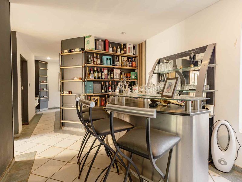 A dedicated home bar area featuring a built-in counter, integrated shelving for storage, and tiled flooring.