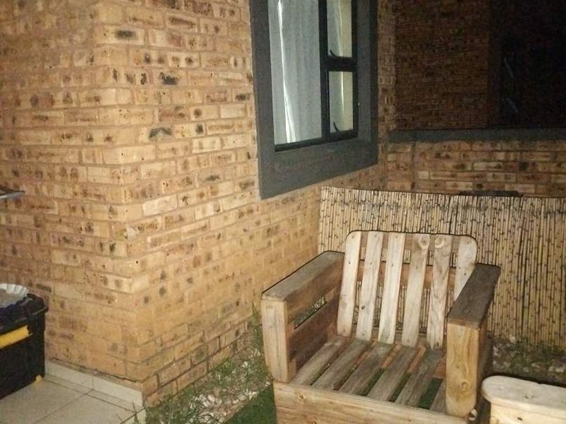 A night view of a rear patio area featuring face brick walls and an aluminium window frame, providing a private outdoor space.