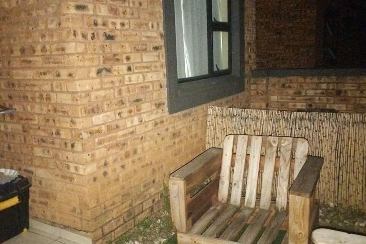 A night view of a rear patio area featuring face brick walls and an aluminium window frame, providing a private outdoor space.