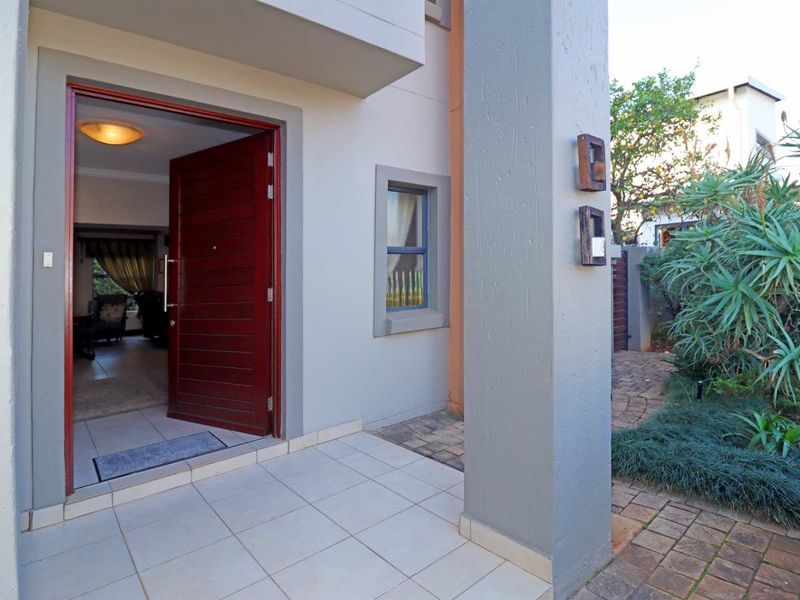 A welcoming front entrance featuring a tiled porch, a solid timber door, and a paved walkway leading to the main house entry.