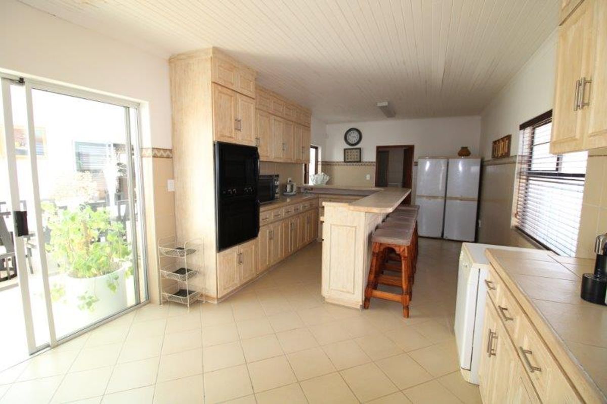 Spacious kitchen featuring light wood cabinetry, a breakfast bar, tiled flooring, and direct access to an outdoor patio area through sliding glass doors.