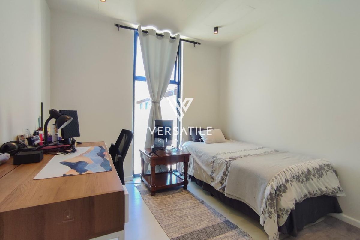 A well-lit bedroom featuring tiled flooring, ceiling-mounted spotlights, and a large full-height window providing natural light.