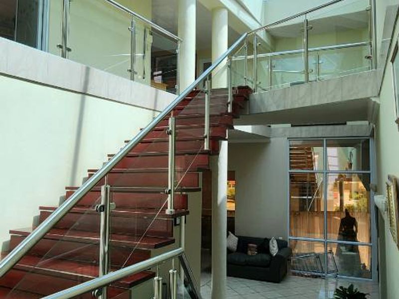 Spacious entrance hall featuring a grand staircase with glass balustrades and a large overhead skylight, creating a bright and airy atmosphere.