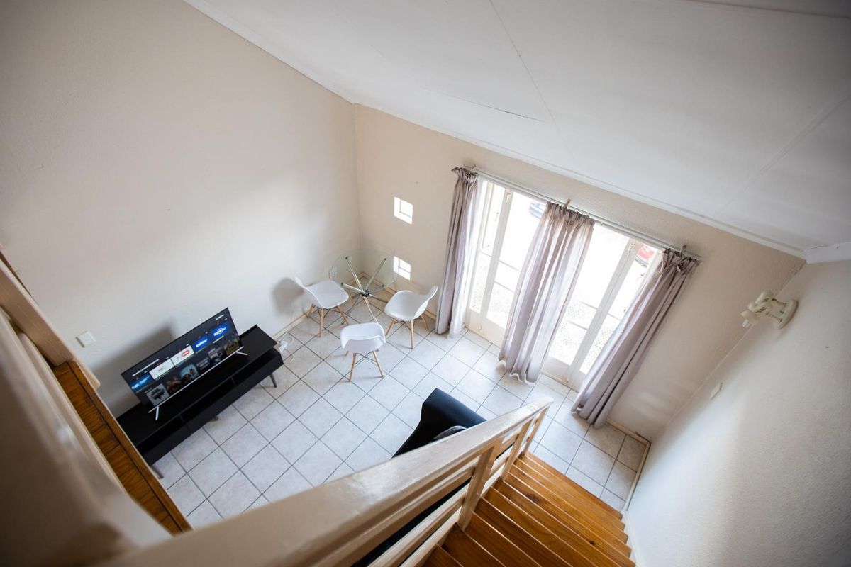 A high-angle view of a living area featuring tiled floors, a vaulted ceiling, and double glass doors leading to an outdoor space.