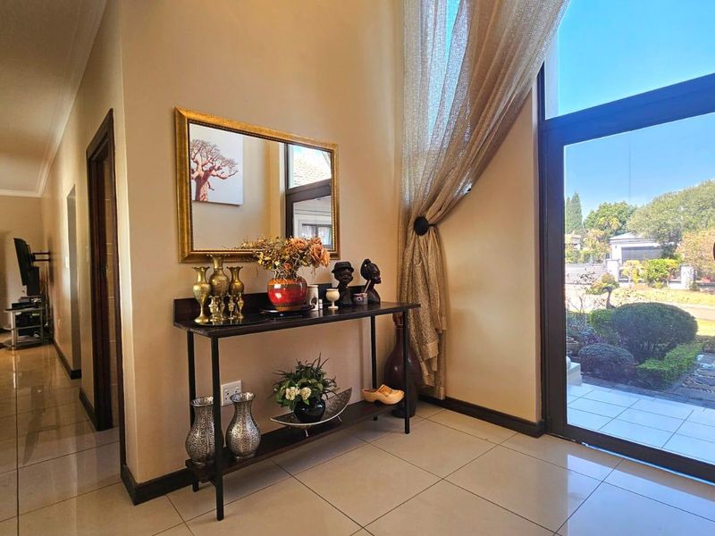 Bright and welcoming entrance hall featuring large glass door, tiled flooring, and recessed lighting, providing a seamless transition to the home's interior.