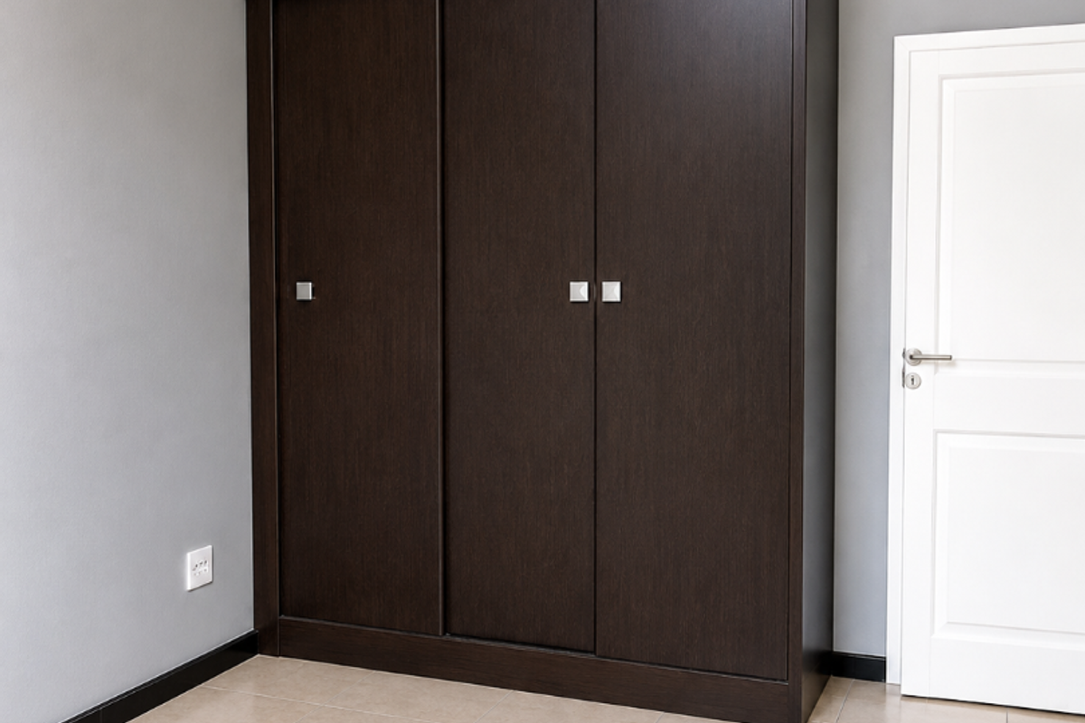 A clean, empty bedroom featuring neutral grey walls, tiled flooring, and a large dark wood built-in wardrobe with sliding doors.