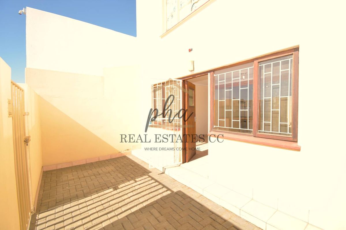 A private rear courtyard featuring paved flooring and direct access to the apartment interior through a door with security bars.