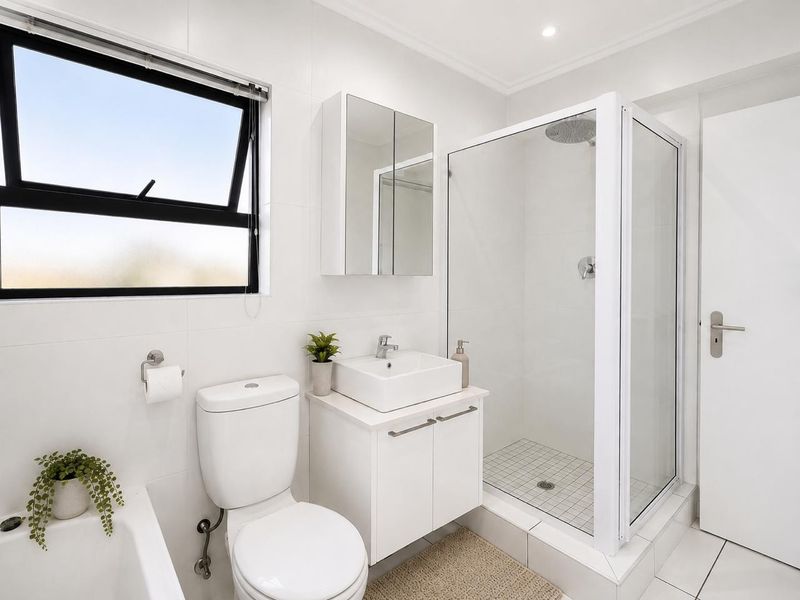 Modern, well-maintained bathroom featuring a glass-enclosed shower, vessel sink vanity, mirrored medicine cabinet, and clean white tiling throughout.