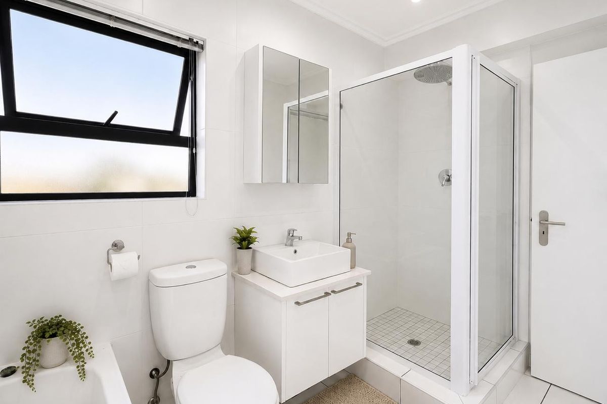 Modern, well-maintained bathroom featuring a glass-enclosed shower, vessel sink vanity, mirrored medicine cabinet, and clean white tiling throughout.