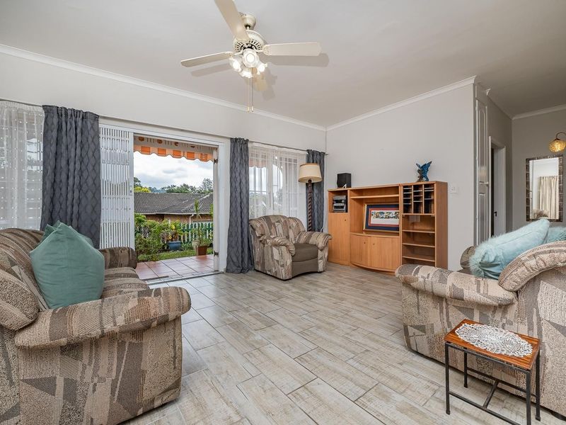 A spacious living room featuring tiled flooring, a ceiling fan, and direct access to an outdoor patio area through sliding glass doors.
