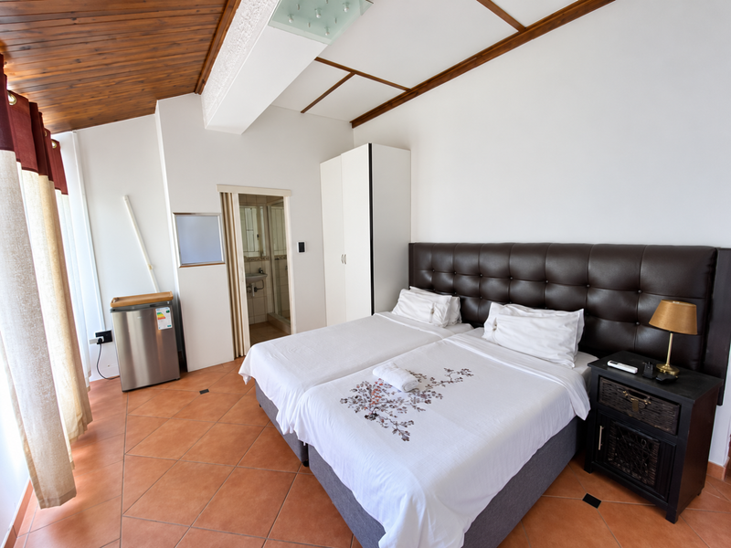 A well-maintained bedroom featuring tiled flooring, a timber-paneled ceiling, and an integrated wardrobe, with direct access to an en-suite bathroom.