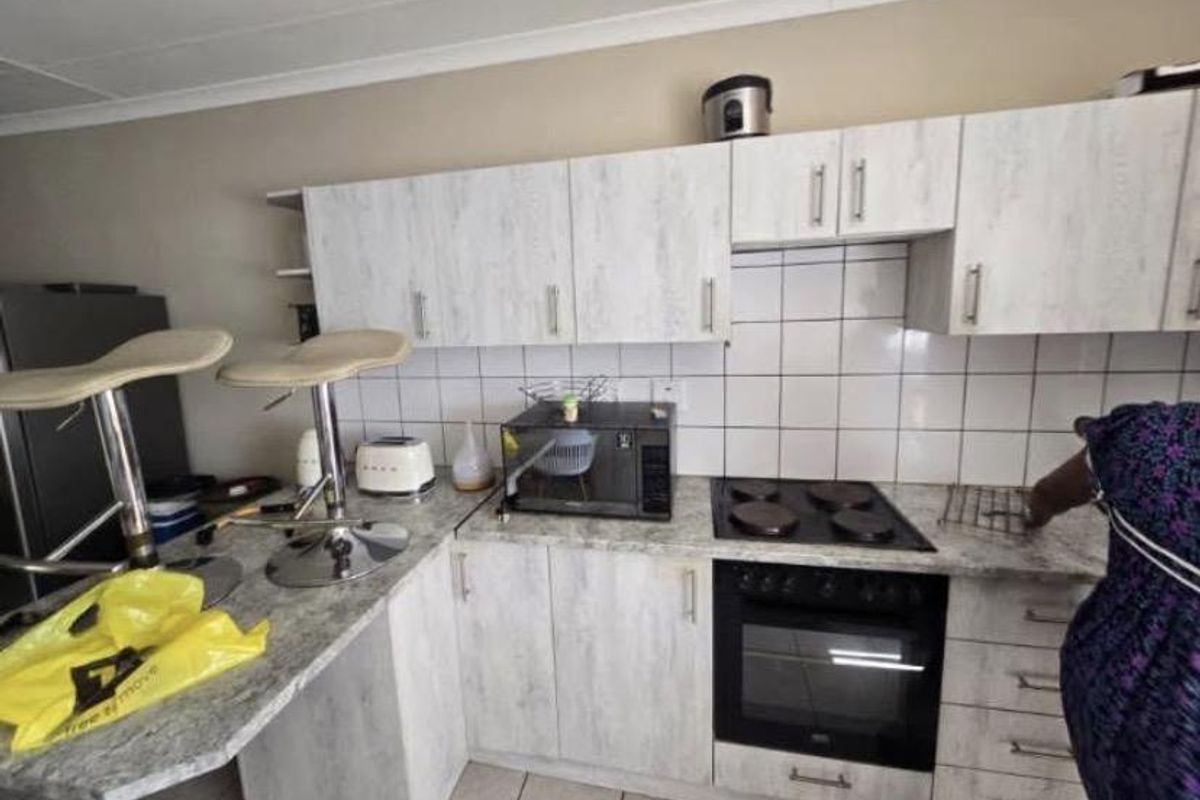 A functional kitchen featuring light wood-grain cabinetry, tiled backsplash, and integrated appliances including an electric hob and oven.