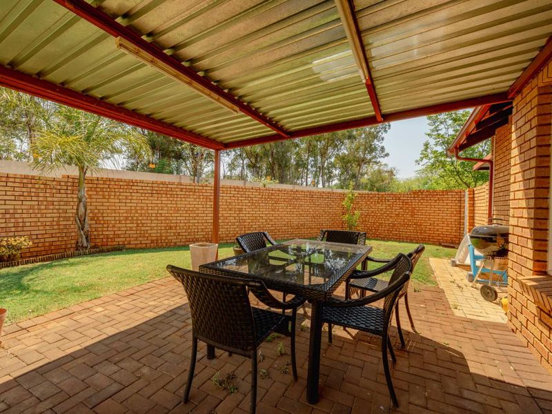 Covered outdoor patio area featuring brick paving and a facebrick boundary wall, providing a functional space for outdoor dining and relaxation.