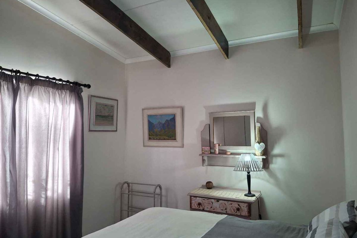 A cozy bedroom featuring exposed timber ceiling beams and neutral wall finishes, providing a comfortable and inviting atmosphere.