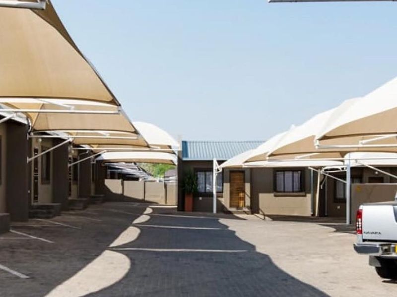 A paved driveway area featuring multiple shade sail carports providing covered parking for the townhouse complex.