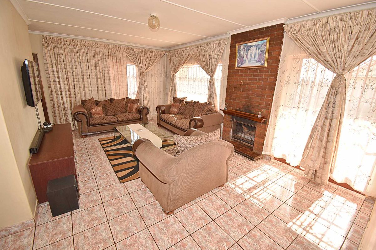 A living room featuring tiled flooring and a prominent brick fireplace, offering a functional space with traditional finishes.