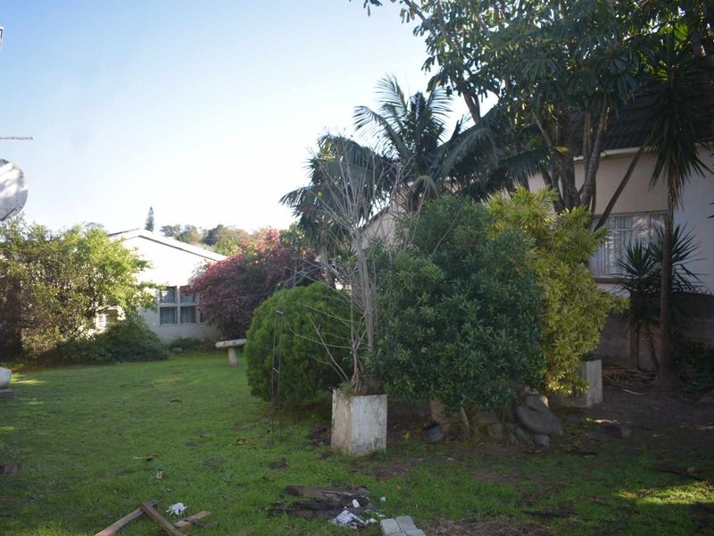 A view of the rear garden area featuring established trees, lawn space, and a satellite dish mounted on the building exterior.