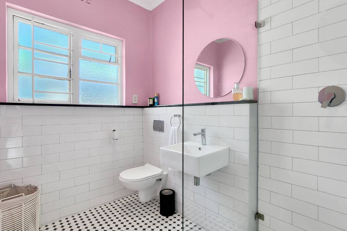 A modern bathroom featuring a wall-mounted basin, wall-hung toilet with concealed cistern, glass shower screen, and classic subway tile finishes.