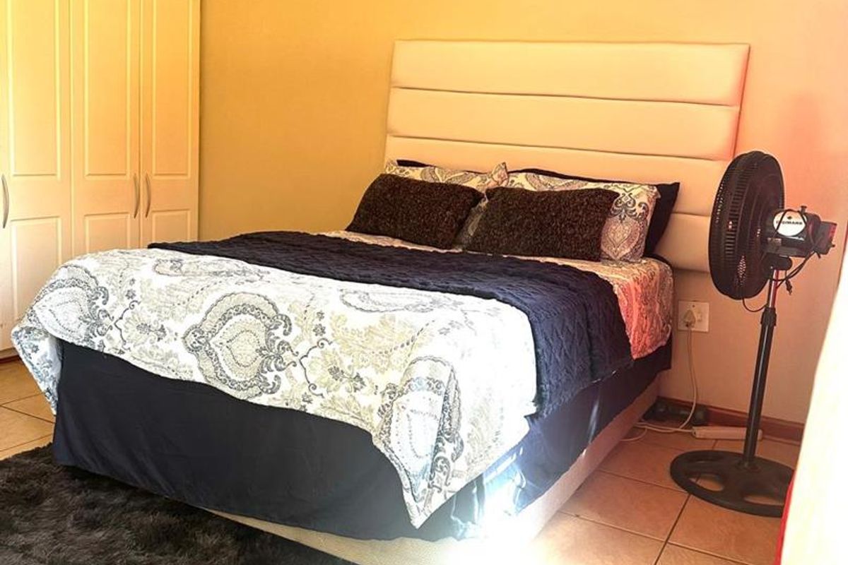 A bedroom featuring built-in cupboards and tiled flooring, providing a functional and neutral living space.