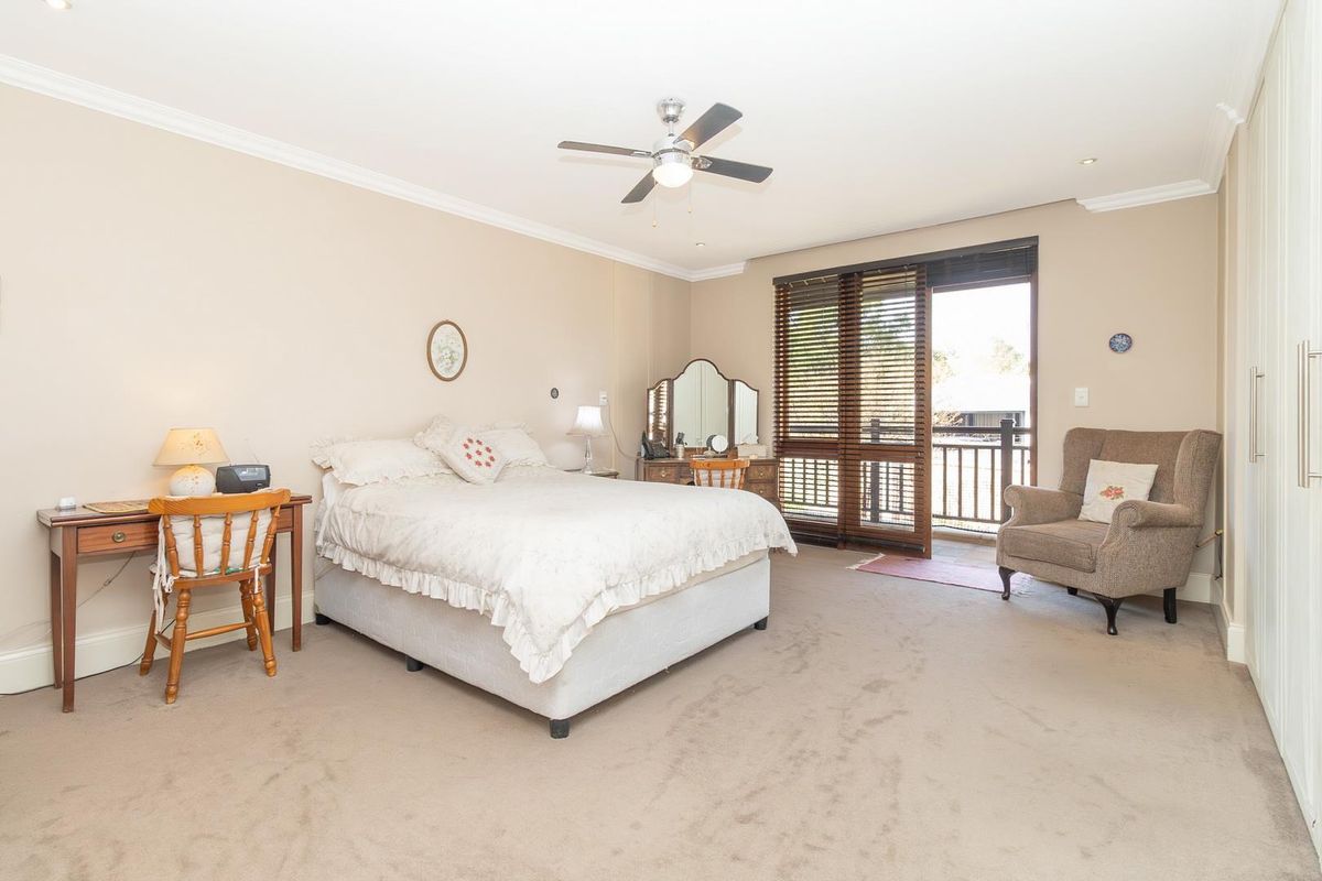 Spacious bedroom featuring neutral walls, ceiling fan, built-in wardrobe, and direct access to a private balcony through sliding glass doors.
