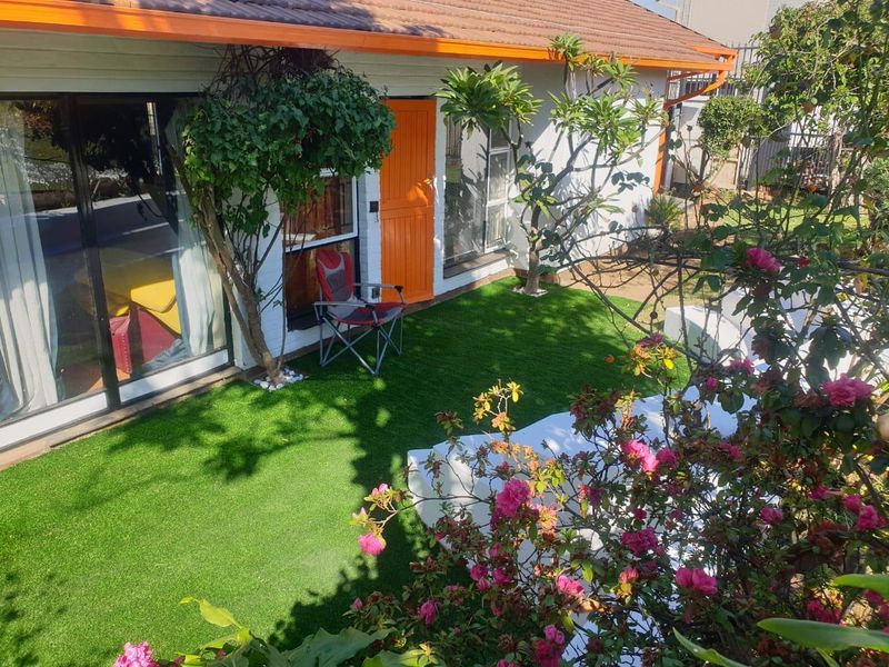 A well-maintained rear garden area featuring artificial turf, built-in seating, and direct access to the home via sliding glass doors.