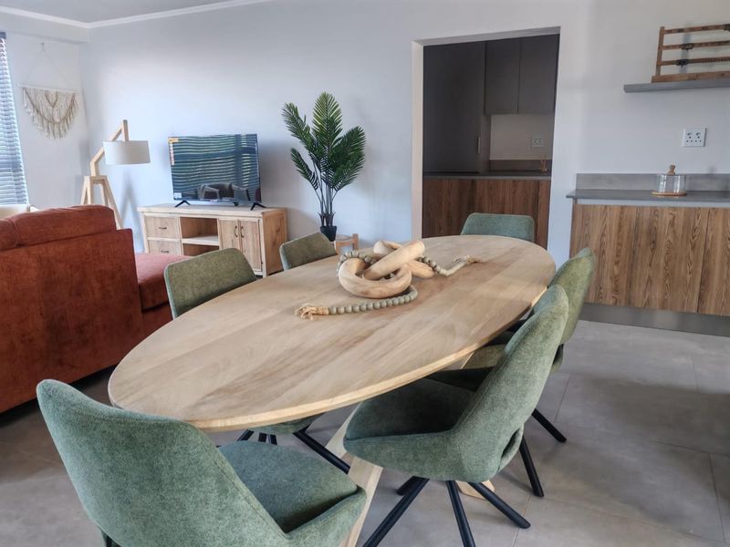 Open plan living and dining area featuring modern kitchen cabinetry with stone countertops and neutral tiled flooring throughout.