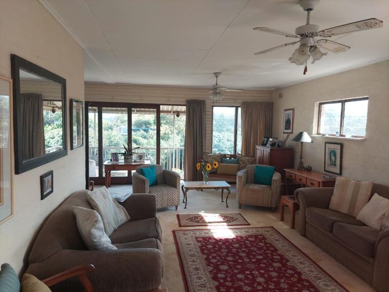 A spacious living room featuring carpet flooring, dual ceiling fans, and large sliding glass doors that provide natural light and access to the outdoors.
