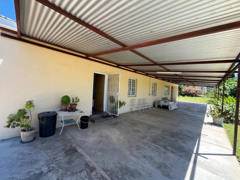 A spacious covered patio area featuring a corrugated metal roof and concrete flooring, providing a functional outdoor space for relaxation or entertaining.