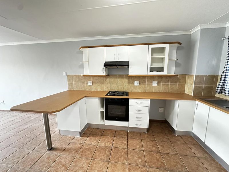 A functional kitchen featuring white cabinetry, laminate countertops, a built-in oven with gas hob, and tiled flooring.