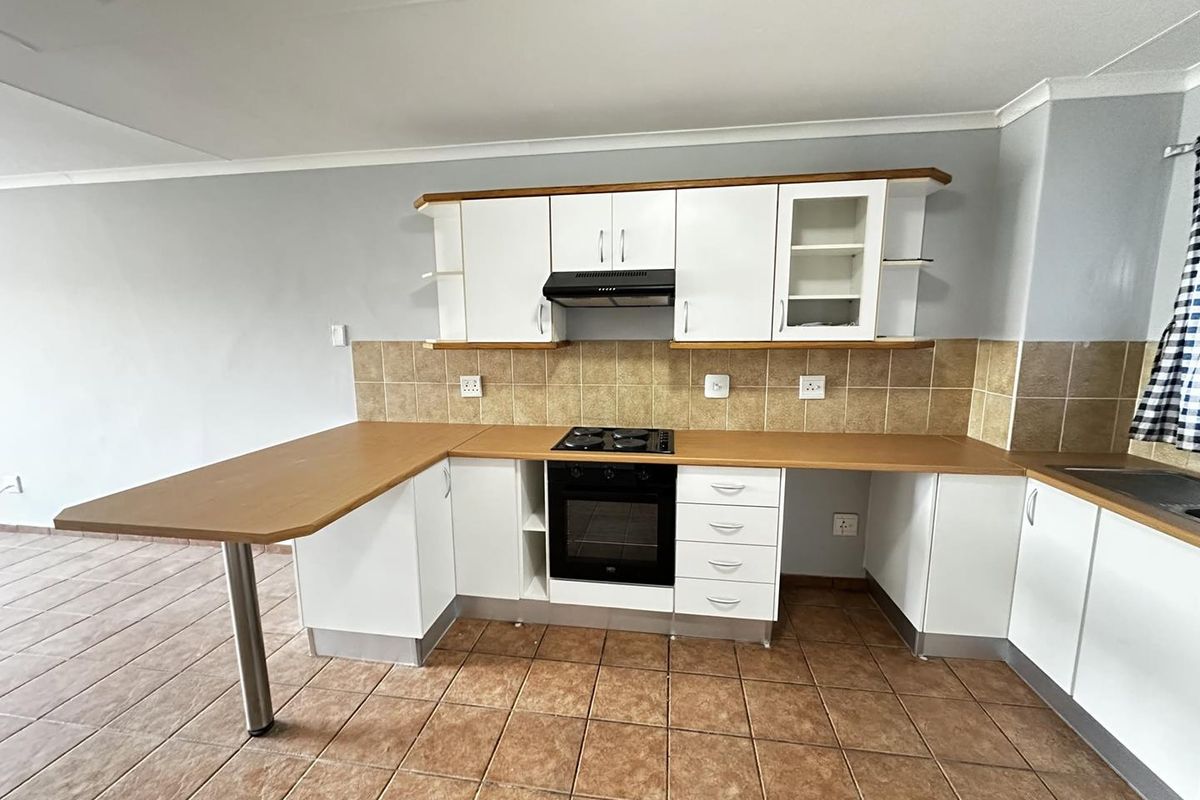 A functional kitchen featuring white cabinetry, laminate countertops, a built-in oven with gas hob, and tiled flooring.