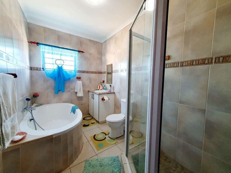 A functional bathroom featuring a corner bathtub, separate shower enclosure, and a built-in vanity with tiled finishes throughout.