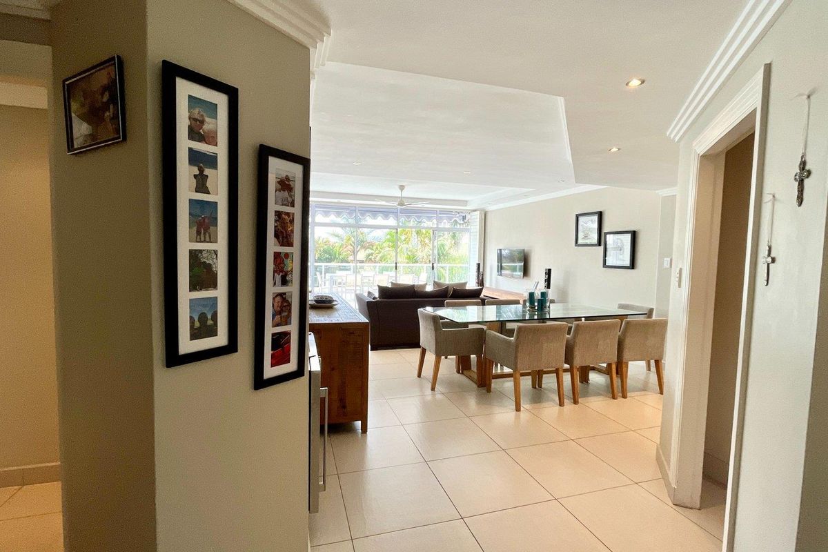 Spacious open-plan living and dining area featuring tiled floors, recessed lighting, and large sliding doors leading to an outdoor balcony.
