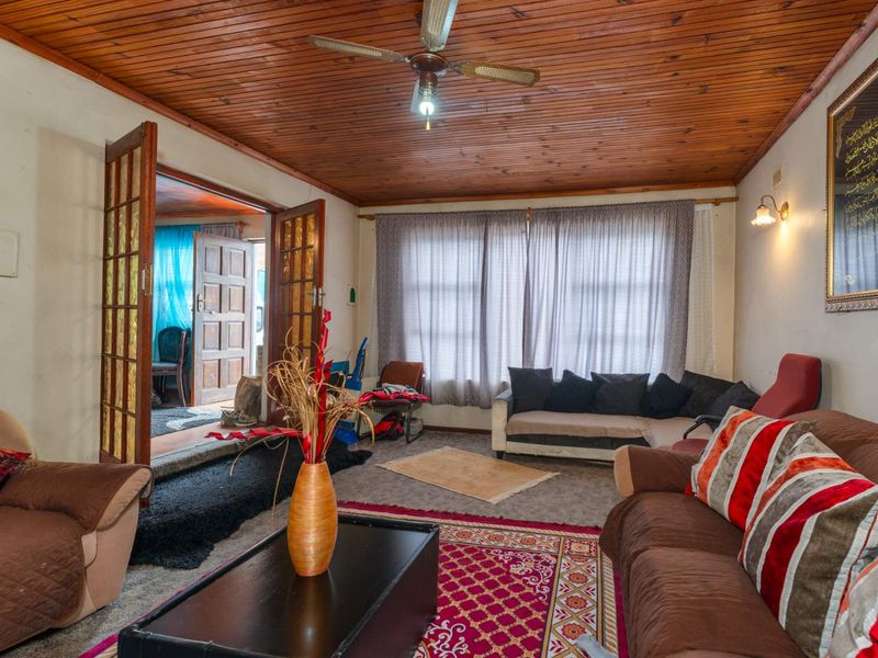 A living room featuring a timber-clad ceiling, ceiling fan, and double timber-framed doors leading to an adjacent space.