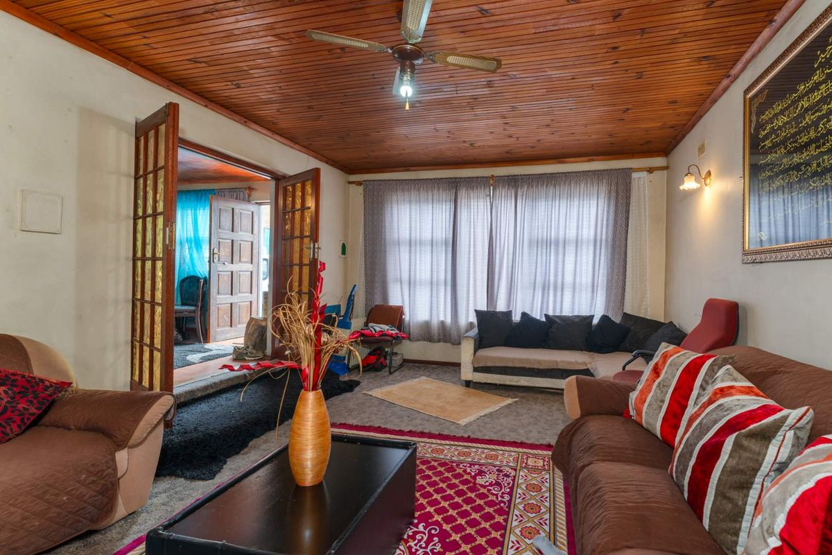 A living room featuring a timber-clad ceiling, ceiling fan, and double timber-framed doors leading to an adjacent space.