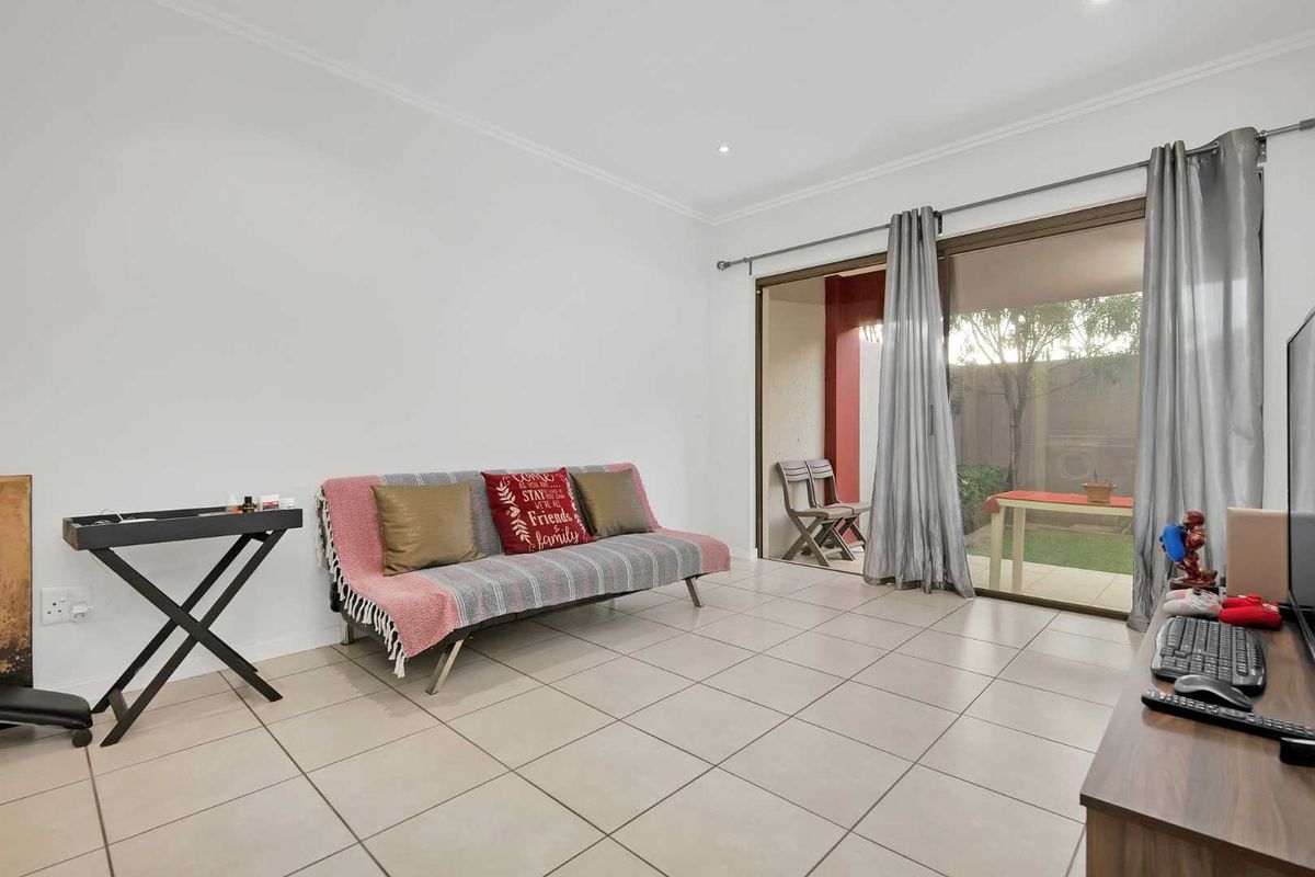 A bright living room featuring neutral floor tiles and large sliding glass doors that provide direct access to an outdoor patio area.