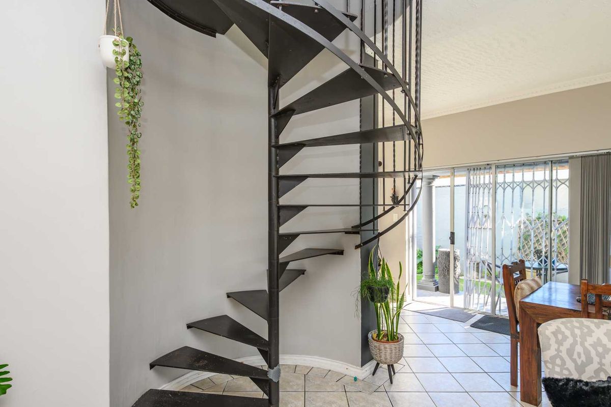 Interior view featuring a black metal spiral staircase, tiled flooring, and sliding glass doors leading to an outdoor area.