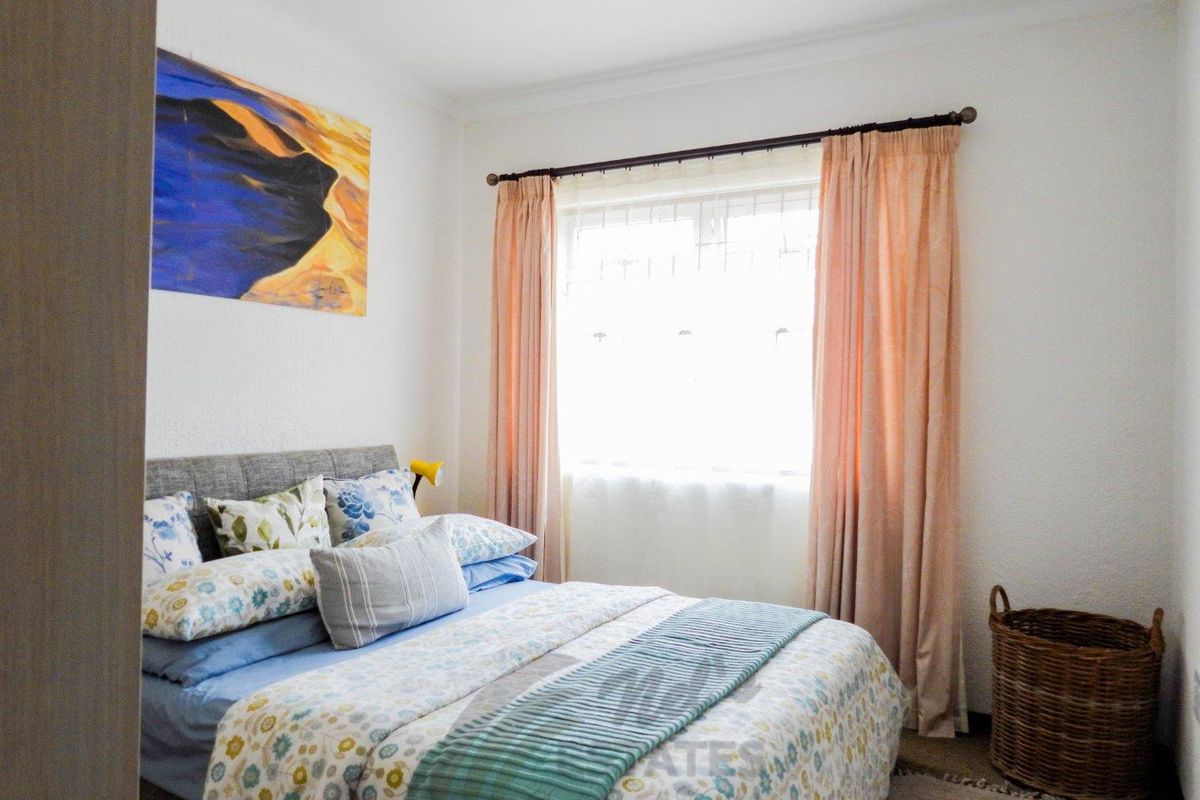 A cozy bedroom featuring a window with curtain rods and neutral wall finishes, providing a comfortable and functional sleeping space.