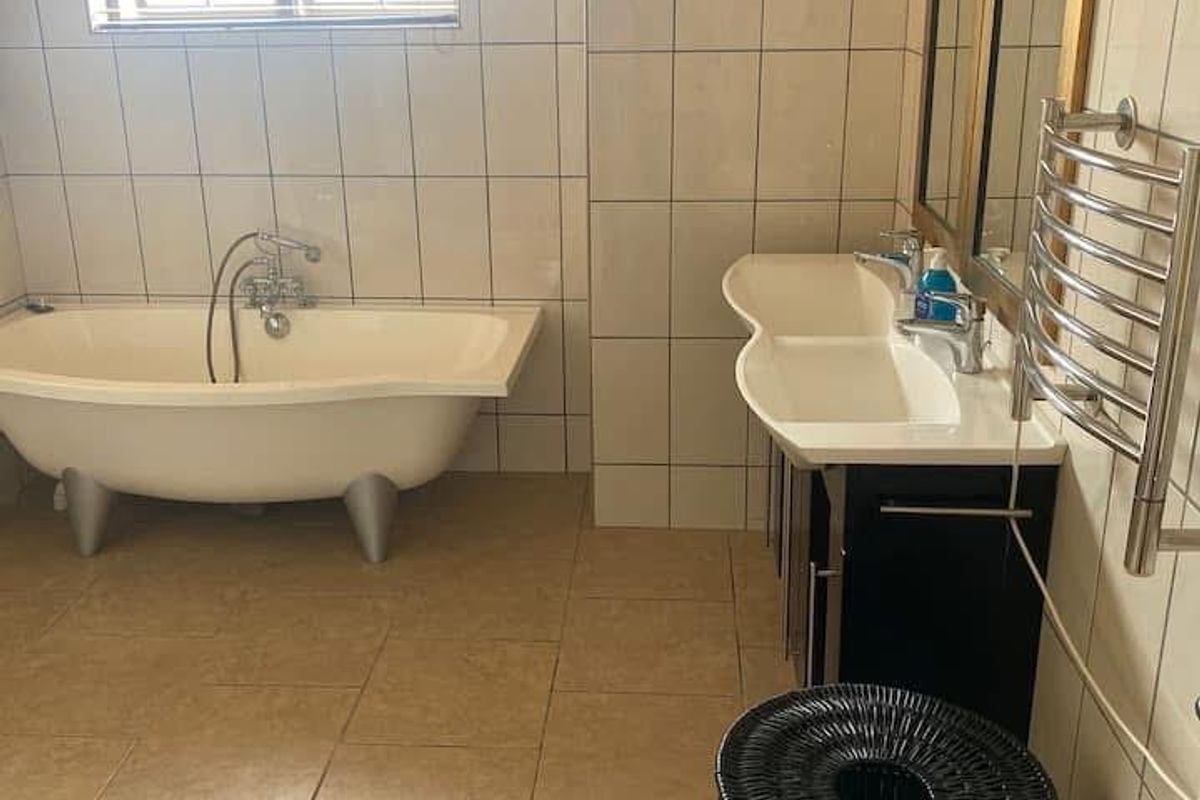 A functional bathroom featuring a freestanding bathtub, double vanity with integrated sinks, and a wall-mounted heated towel rail.