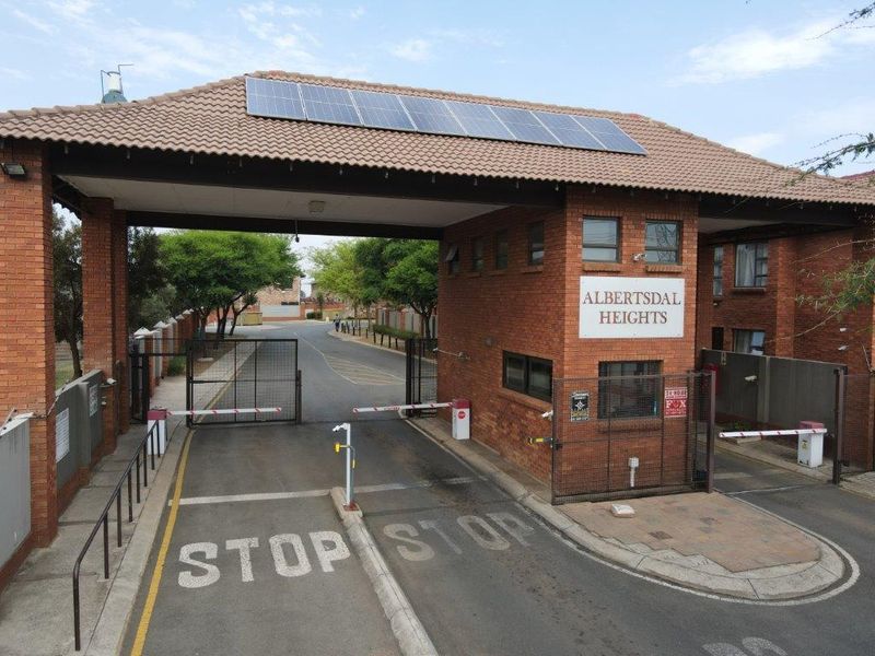 The secure entrance gate of Albertsdal Heights, featuring a brick guard house, boom gate access control, and roof-mounted solar panels.