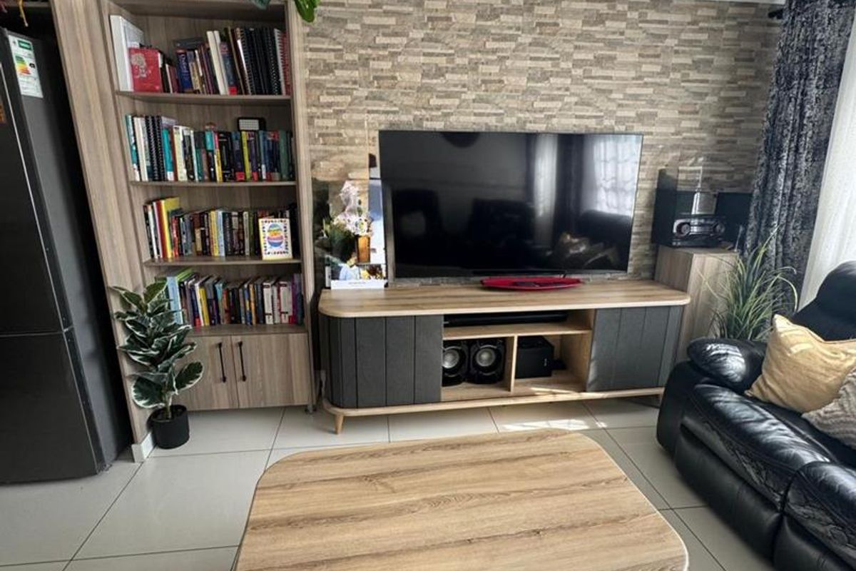 A living room featuring large format floor tiles and a decorative stone-cladding feature wall.
