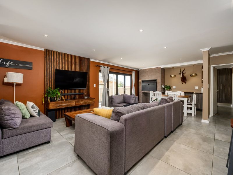 Spacious open-plan living area featuring large format floor tiles, a modern timber slat feature wall, built-in fireplace, and seamless access to the outdoor space.