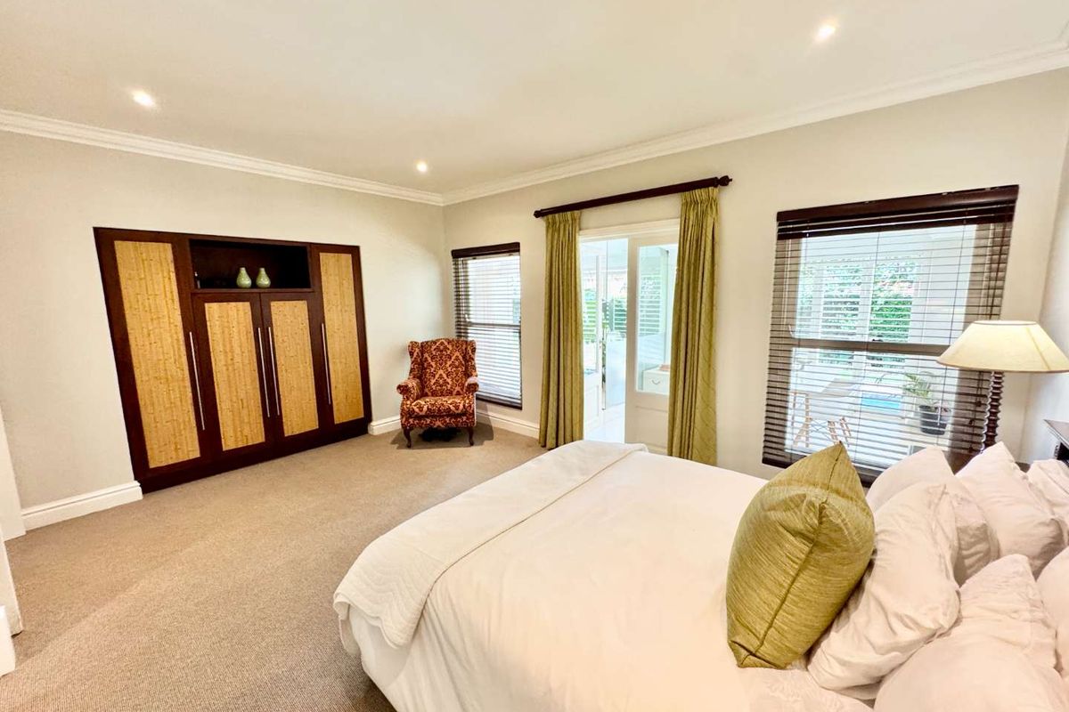 Spacious bedroom featuring built-in cabinetry, neutral carpeting, and direct access to an outdoor patio area through glass sliding doors.