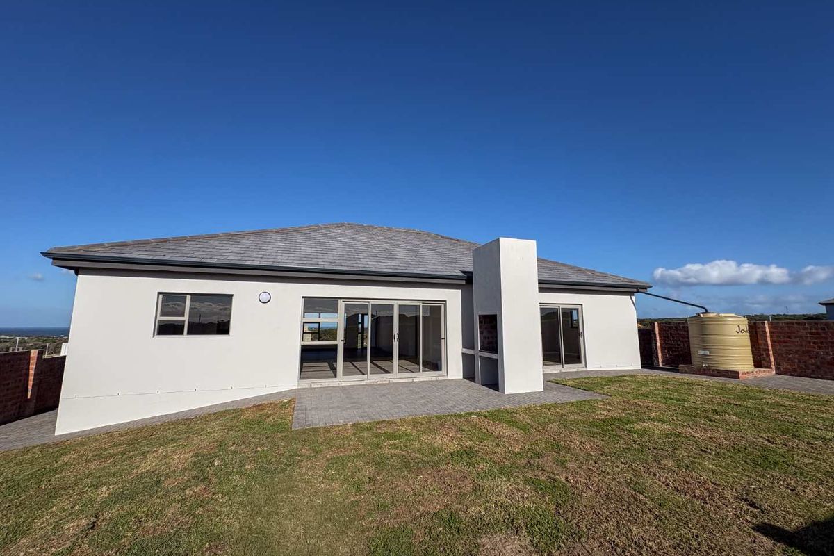 Rear view of the property featuring a paved patio area, built-in braai, sliding glass doors, and a water storage tank.