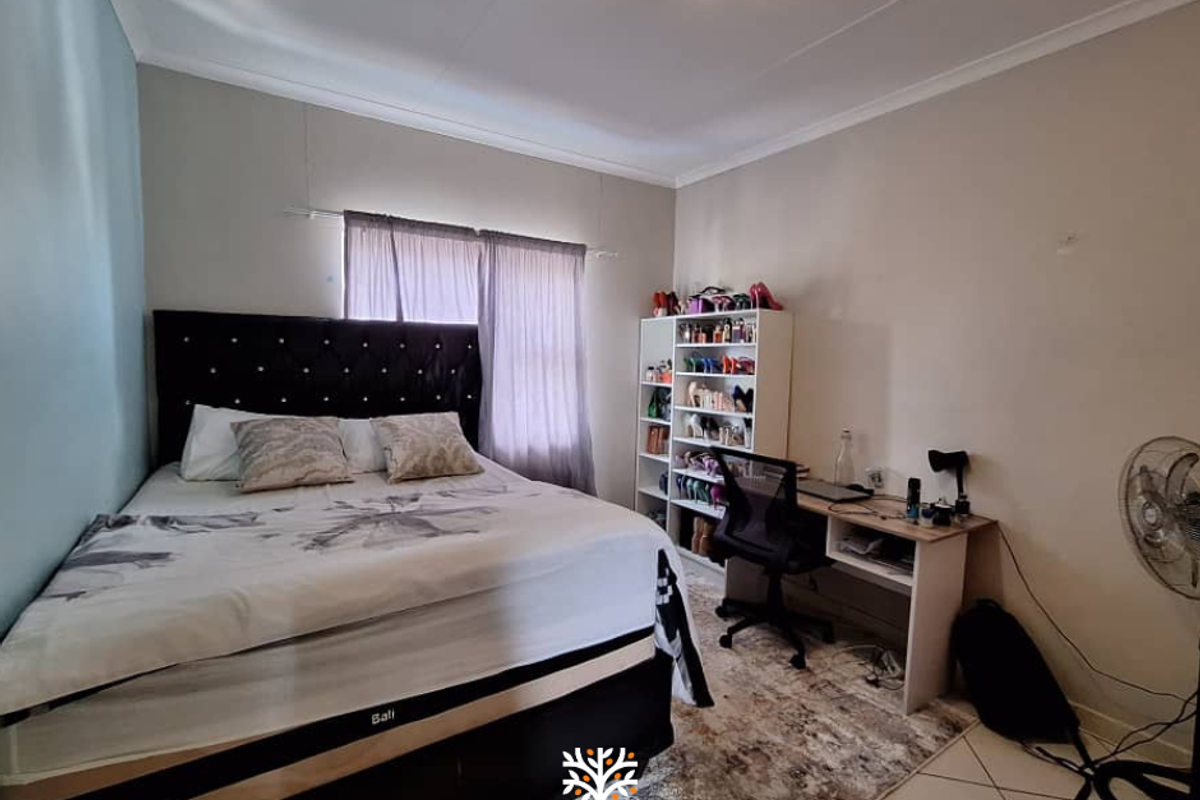 A functional bedroom featuring tiled flooring, neutral wall tones, and a window with curtain tracks.