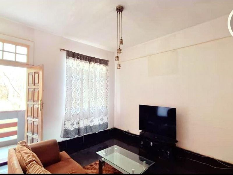 A living room featuring tiled flooring, a pendant light fixture, and direct access to an outdoor balcony area.