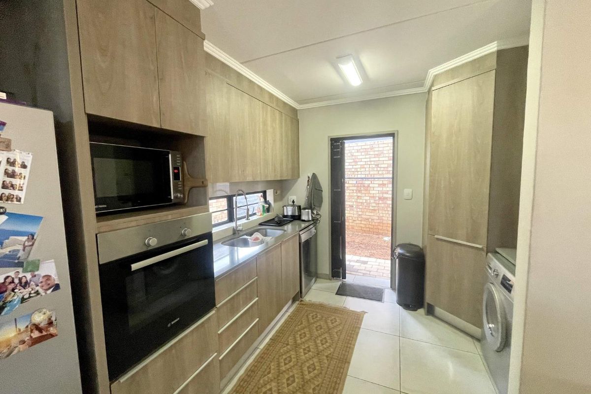 A functional kitchen featuring wood-look cabinetry, built-in oven, microwave, stainless steel sink, and direct access to an exterior courtyard area.
