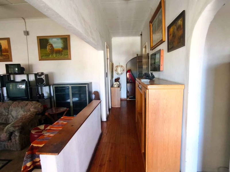 A living area featuring timber flooring, an arched doorway, and an exposed ceiling beam, providing a traditional layout with potential for modernization.