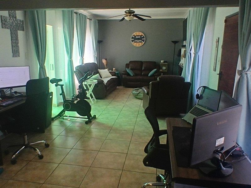 Spacious living area featuring tiled flooring, a ceiling fan, and access to the outdoors via a sliding glass door.